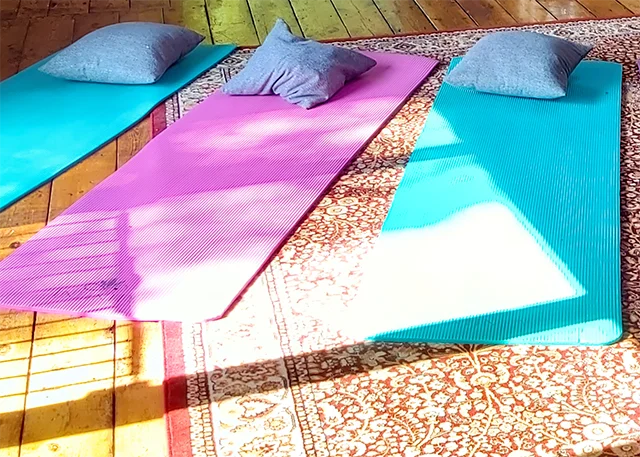 Three mats with cushions laid out on a patterned rug, ready for a sound bath
