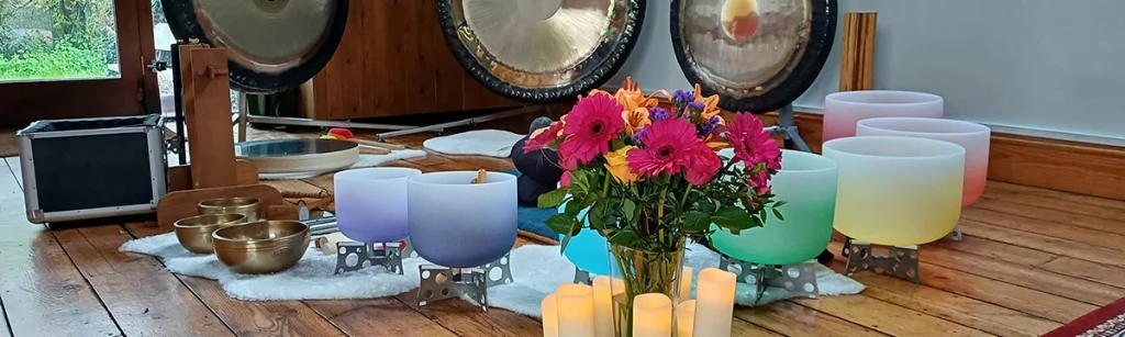 Gongs, crystal bowls, brass bowls, flowers and candles set up for a sound bath at Eden Rise